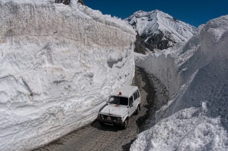 ZOJILA, KASHMIR, INDIA - APRIL 30: An vehicle  passes through the snow-cleared Srinagar-Leh highway on April 30, 2016 in Zojila, 108 km (67 miles) east of Srinagar, the summer capital of Indian administered Kashmir, India. The 443 km (275 miles) long Srinagar-Leh highway was opened for vehicles by Indian Border Roads Organisation after remaining snowbound at Zojila Pass for the past five months. The pass connects Kashmir with Ladakh region a famous tourist destination among foreign tourists for its monasteries, landscapes and mountains. The average snow buildup on the rocky territory of Zojila pass normally stays in the level of 15 to 25 meters and is closed for a half of each year. It opens up in late spring and travelers on the pass have to withstand snowstorms, fierce air currents, cold and highly dangerous circumstances. (Photo by Yawar Nazir/Getty Images)
