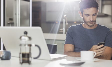 Man texting with cell phone at kitchen table