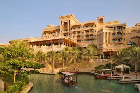 Dubai.  Al Qasr Hotel, built in the style of a Moroccan palace, seen over one of the Madinat Jumeirahs canals with an abra, a water taxi.